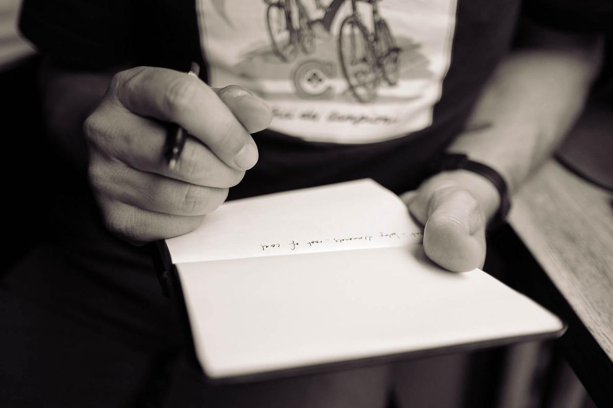 An image depicting a person writing on a notepad with a pen.